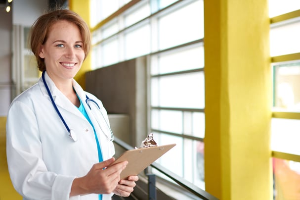 Portrait of a female doctor holding her patient chart in bright modern hospital